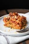 White plate with piece of vegetable lasagna and a fork on it