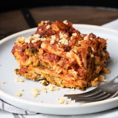 placă albă cu bucată de lasagna de legume și o furculiță pe ea