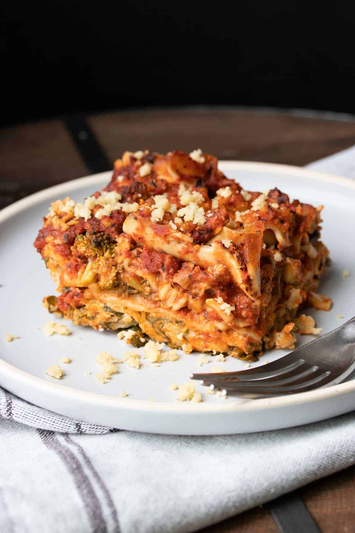 White plate with piece of vegetable lasagna and a fork on it.