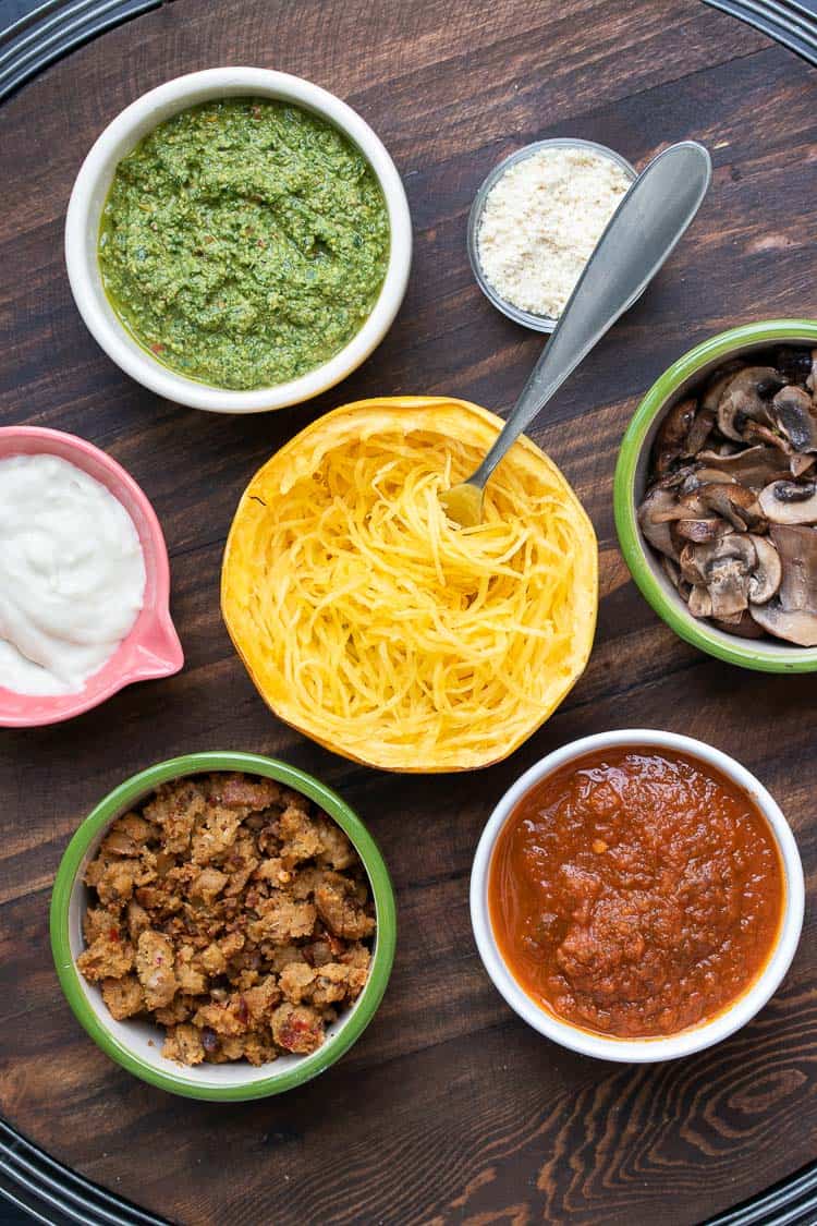 Baked spaghetti squash half with fork in it surrounded by toppings