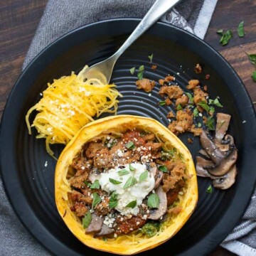 Baked spaghetti squash bowl with toppings on a black plate