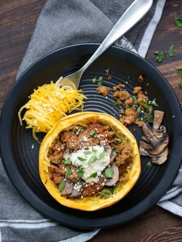 Baked spaghetti squash bowl with toppings on a black plate