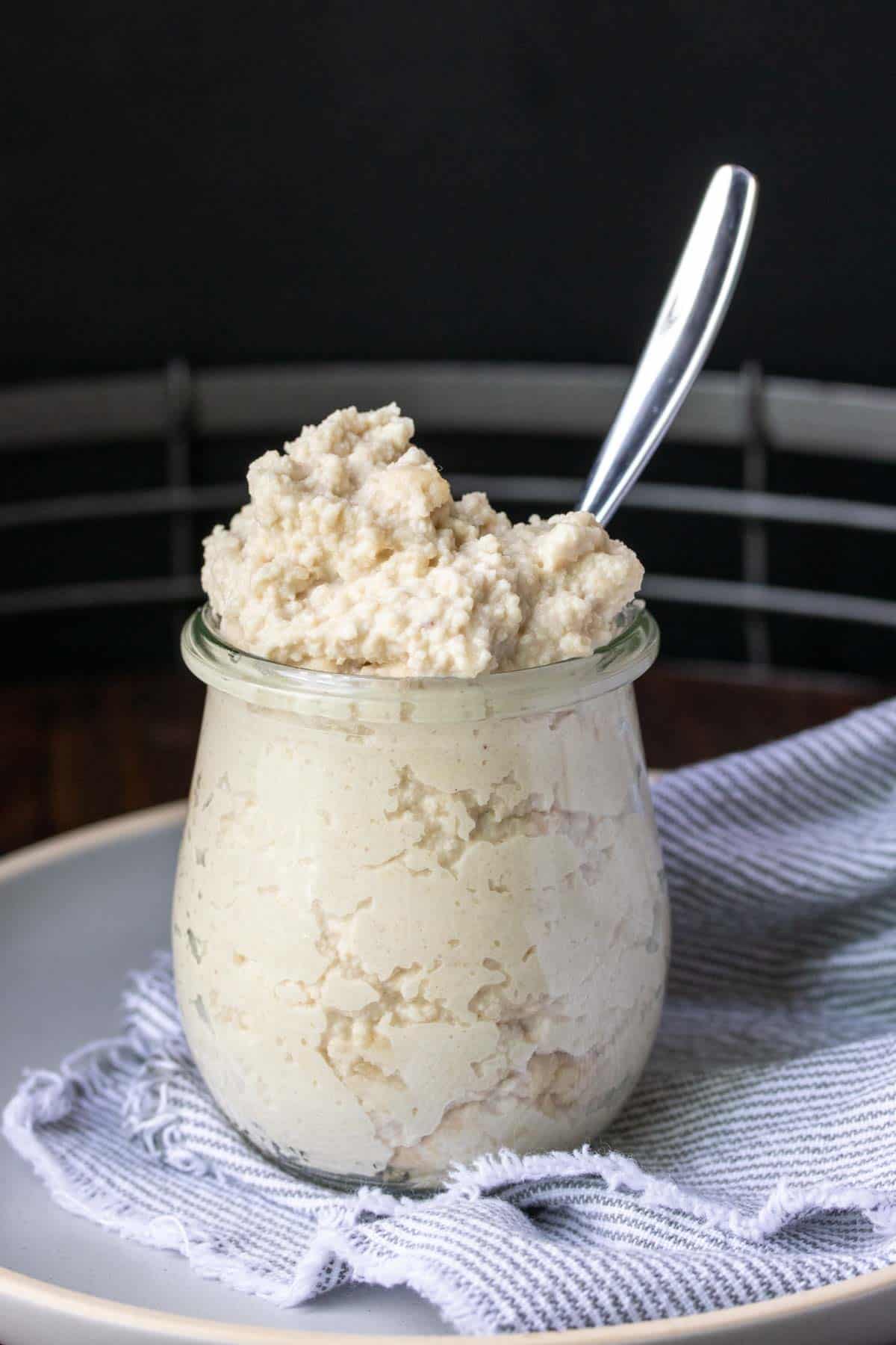 Glass jar with a spoon in it filled with cashew ricotta