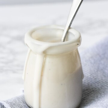Glass jar with walnut cashew cream sauce dripping down the side