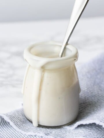 Glass jar with walnut cashew cream sauce dripping down the side.