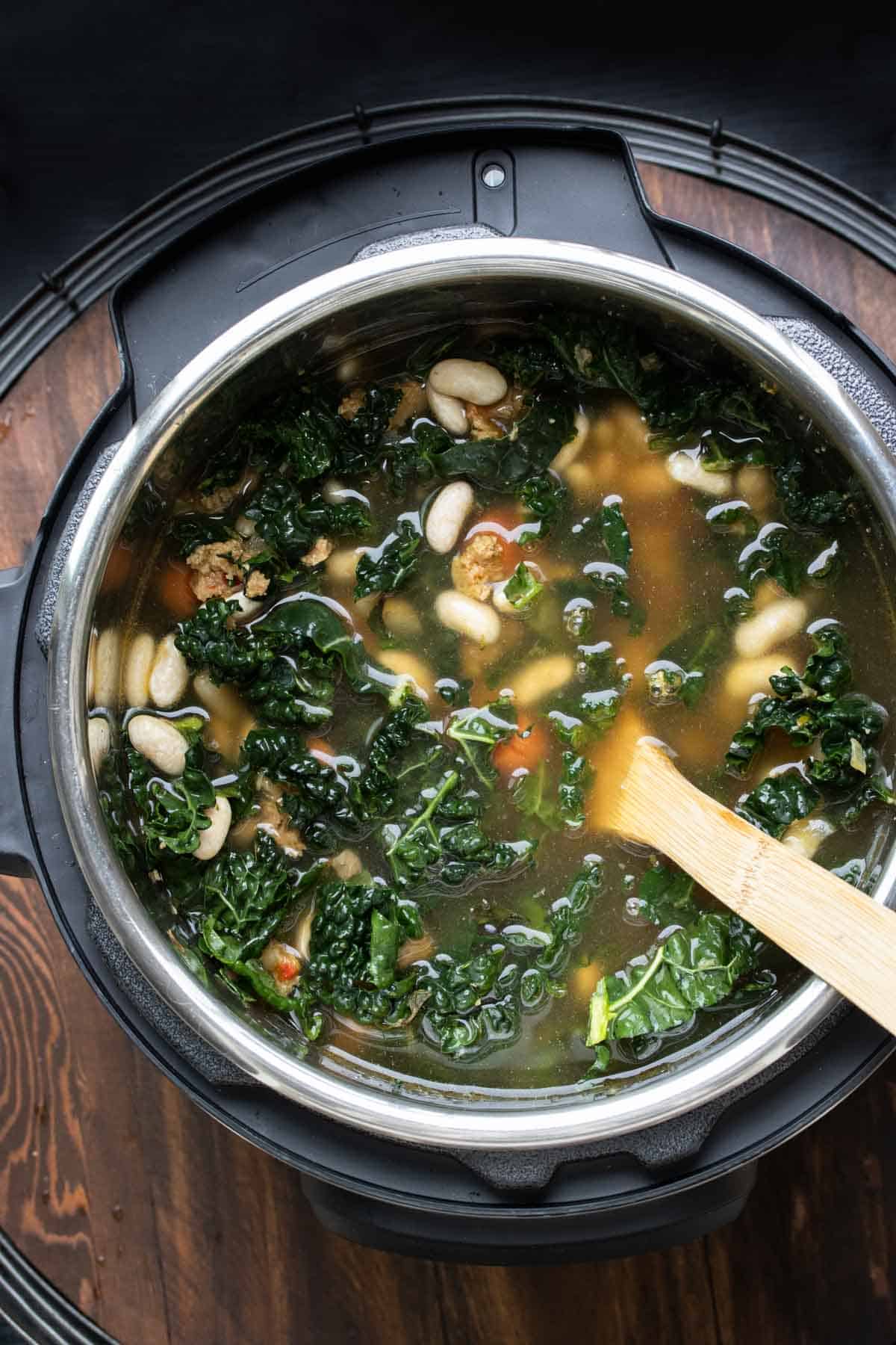 Top view of soup with kale, white beans, carrots and sausage in an instant pot.