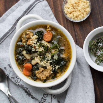 Top view of sausage, kale, white bean and carrot soup on a grey napkin