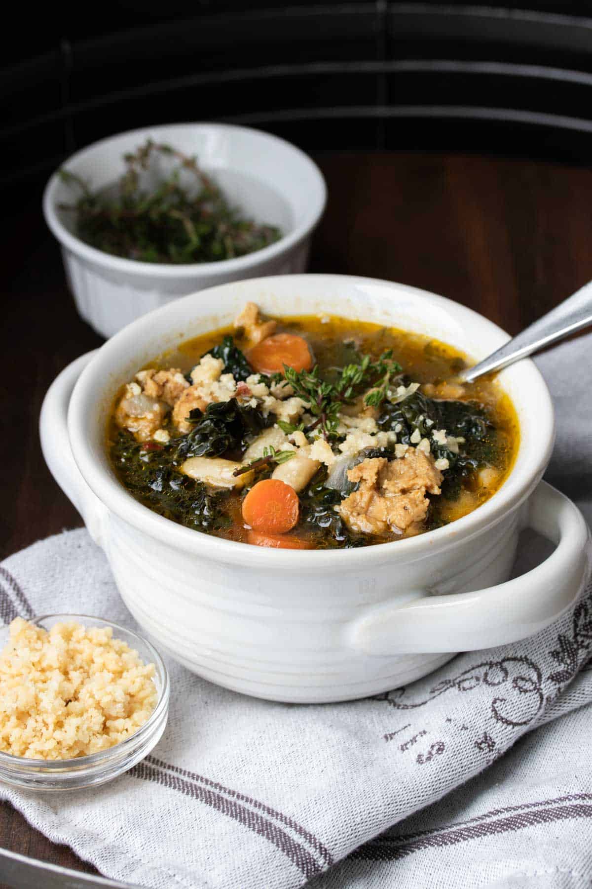 White bowl with kale, carrot, white bean and sausage soup