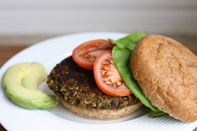 An open veggie bean burger topped with tomato and lettuce