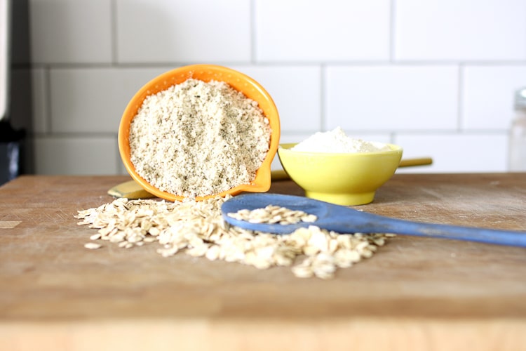 A bowl of quinoa flour on it's side spilling out on to a wooden board