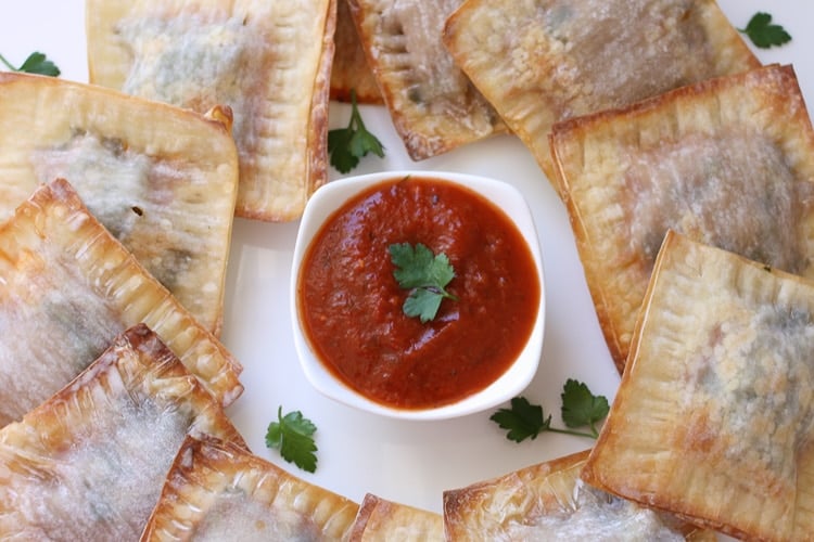 Lasagna wontons on a white plate with red dipping sauce in the middle