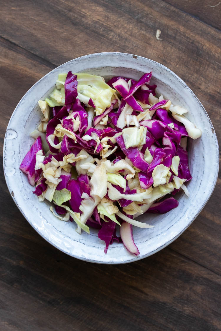 White bowl filled with purple and green shredded cabbage