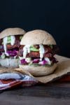 Front view of a BBQ tempeh sandwich in a bread roll with cabbage, avocado, pickles and ranch