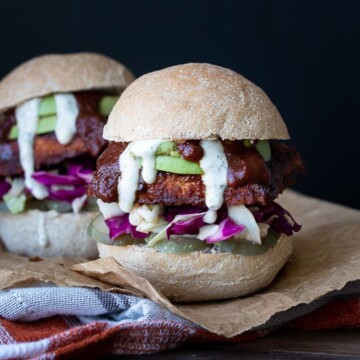 Front view of a BBQ tempeh sandwich in a bread roll with cabbage, avocado, pickles and ranch