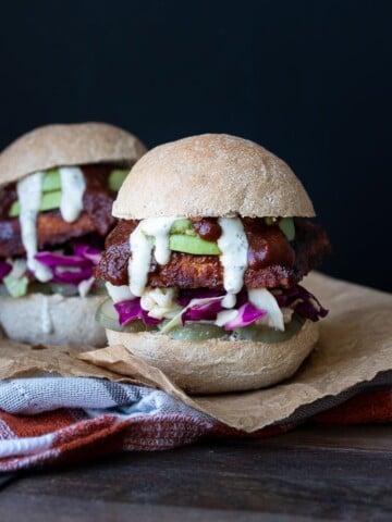 Front view of a BBQ tempeh sandwich in a bread roll with cabbage, avocado, pickles and ranch