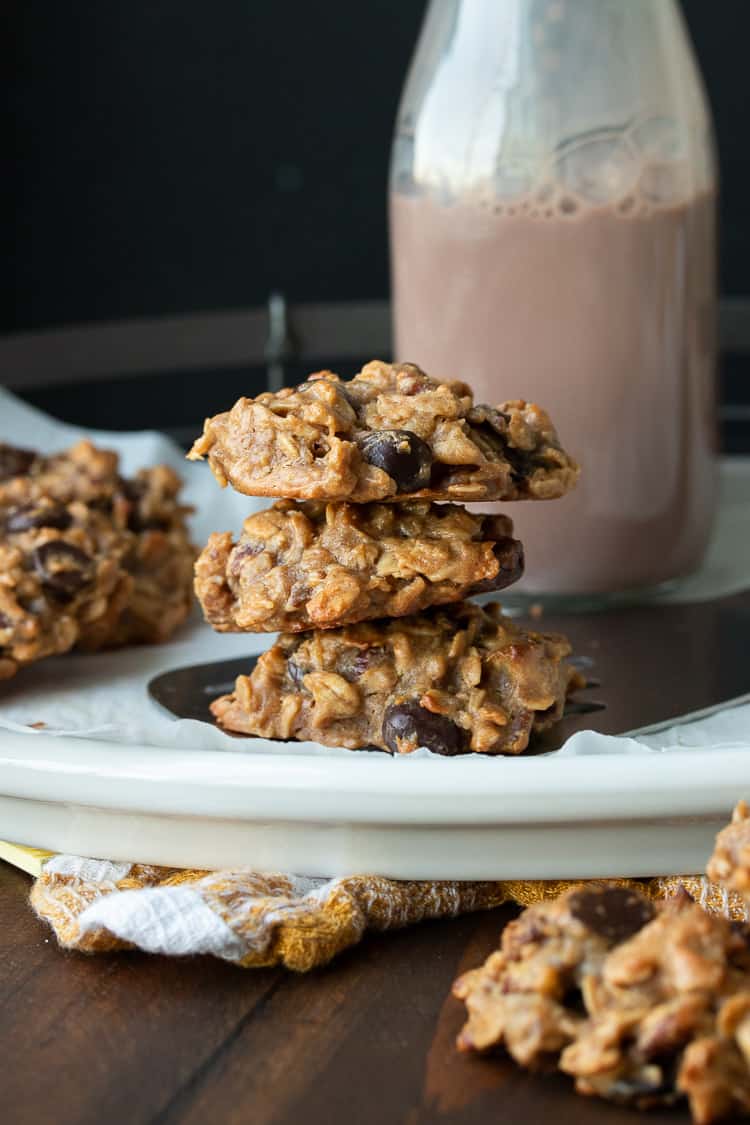 White plate with a pile of oatmeal cookies by a jar of chocolate milk