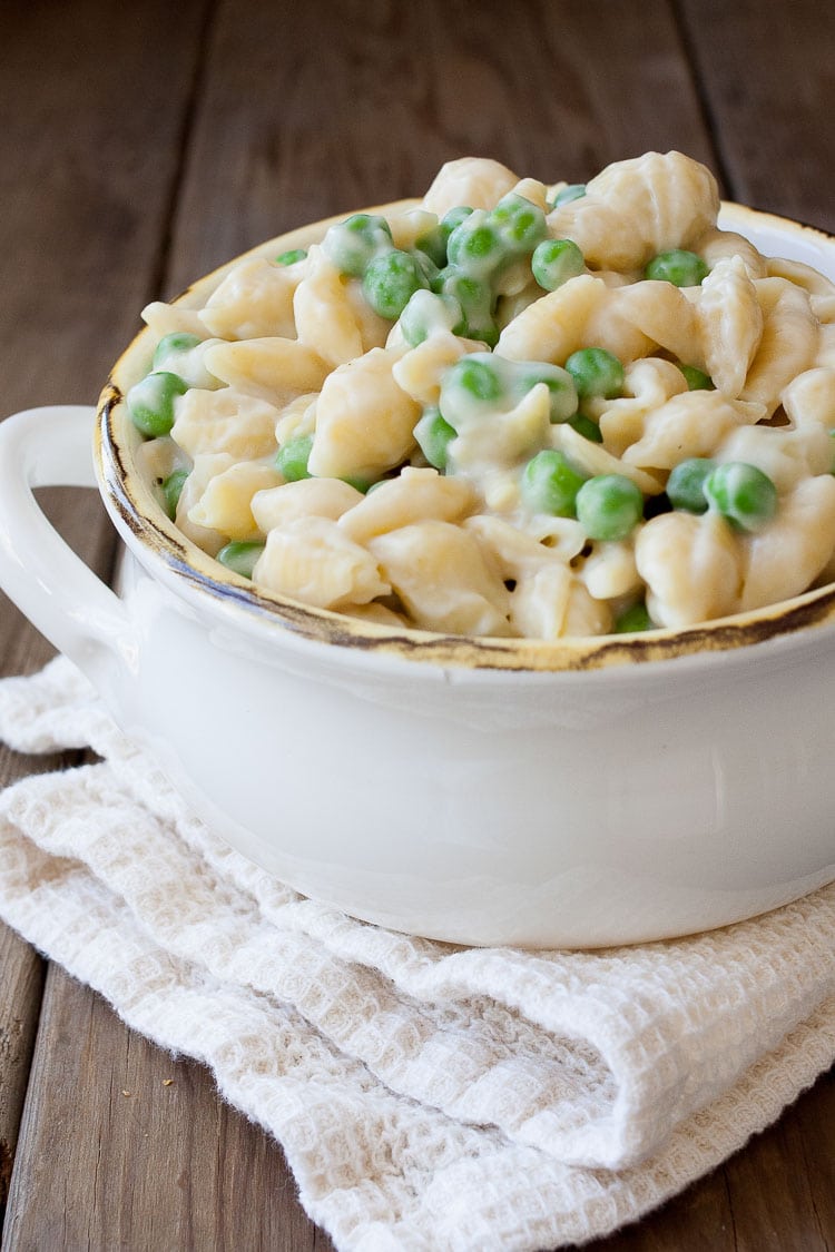 A close up of creamy pasta and peas in a white bowl