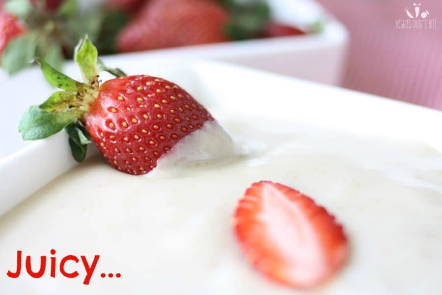 A strawberry being sipped into a Vegan Yogurt Dip