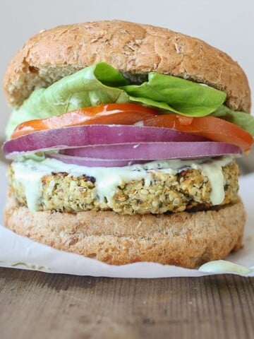 A Cauliflower burger topped with onion, tomato and salad in a burger bun