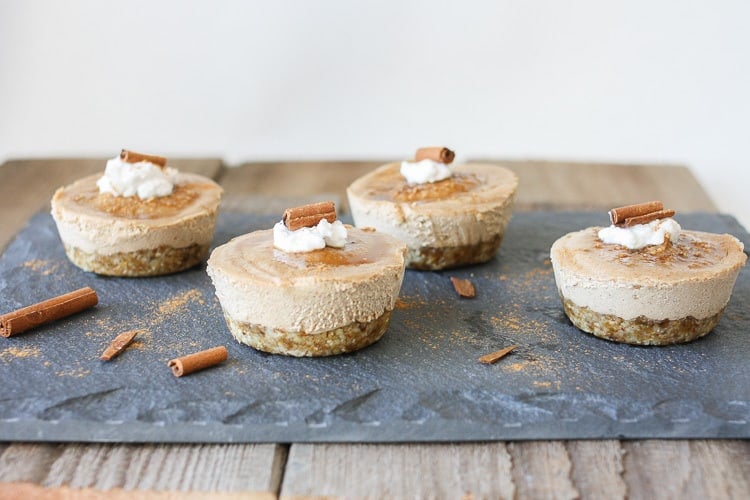 Raw vegan churro cheesecake cups topped with coconut cream and cinnamon sticks