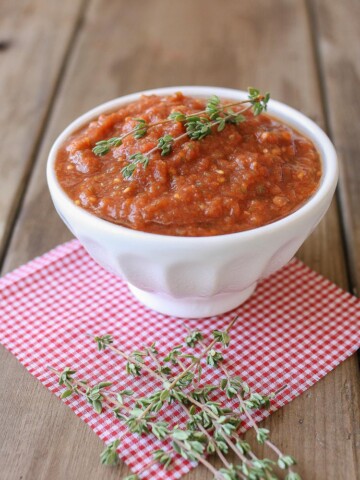 A side shot of raw marinara in a bowl topped with sprigs on thyme
