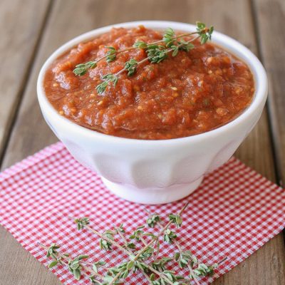 A side shot of raw marinara in a bowl topped with sprigs on thyme
