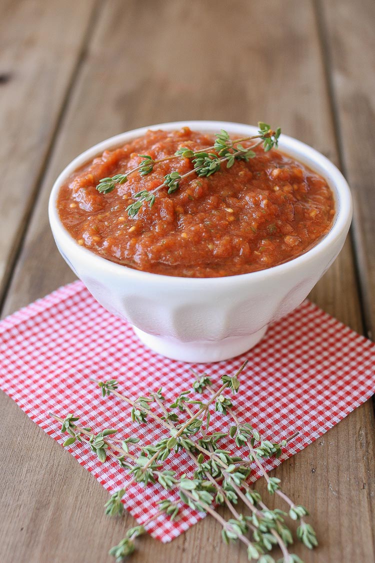 Raw marinara sauce in a small white bowl topped with thyme