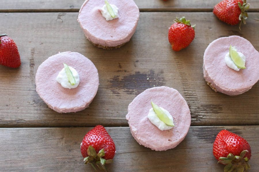 Raw strawberry margarita cheesecake cups on a wooden surface
