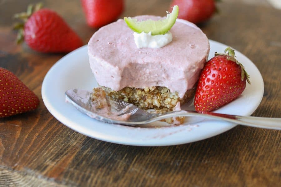 Raw strawberry margarita cheesecake cups on a plate with a bite out