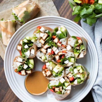 Cut summer rolls on a white plate with brown dipping sauce