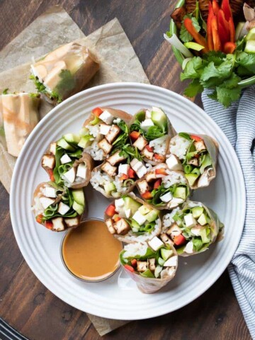 Cut summer rolls on a white plate with brown dipping sauce