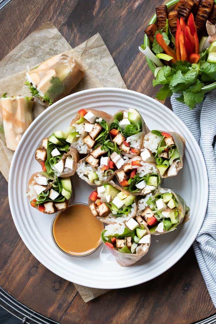 Cut summer rolls on a white plate with brown dipping sauce