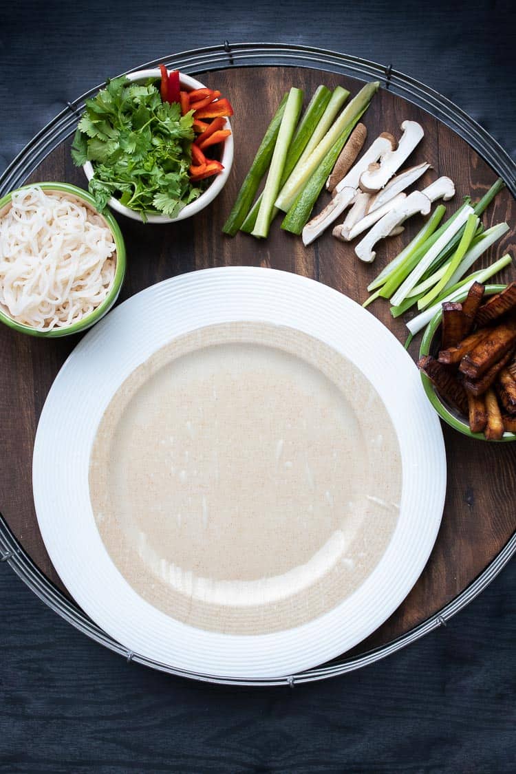 Rice paper on white plate surrounded by veggies