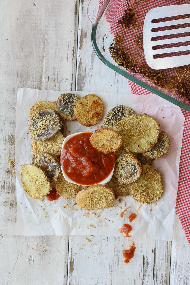 An overhead shot of Hemp Almond Parmesan Potato Chip Rounds on a wooden surface with tomato sauce