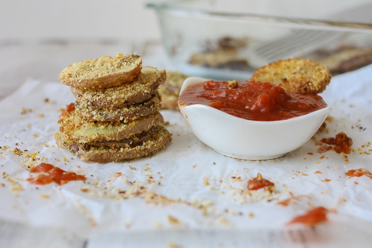 A stack of Hemp Almond Parmesan Potato Chip Rounds on parchment paper with a tomato dipping sauce