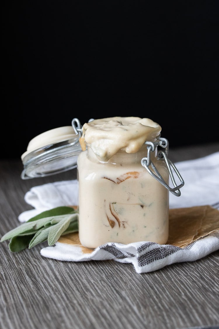 Front view tan creamy sauce with caramelized onions and sage in glass jar