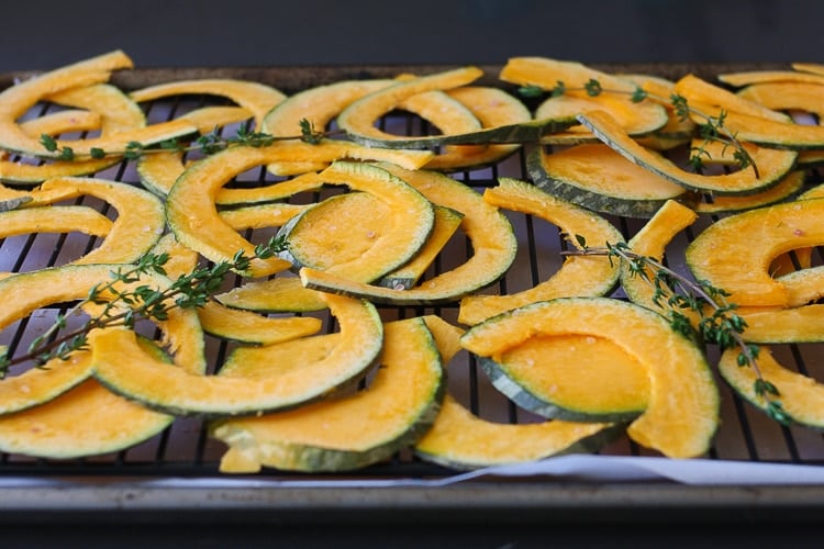 Slices of Baked Kabocha chips with thyme on a cooling rack