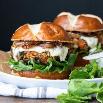 Front view of butternut squash burger on a pretzel roll with ranch, caramelized onions and lettuce