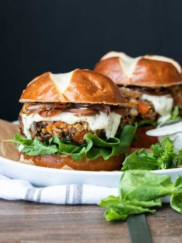 Front view of butternut squash burger on a pretzel roll with ranch, caramelized onions and lettuce