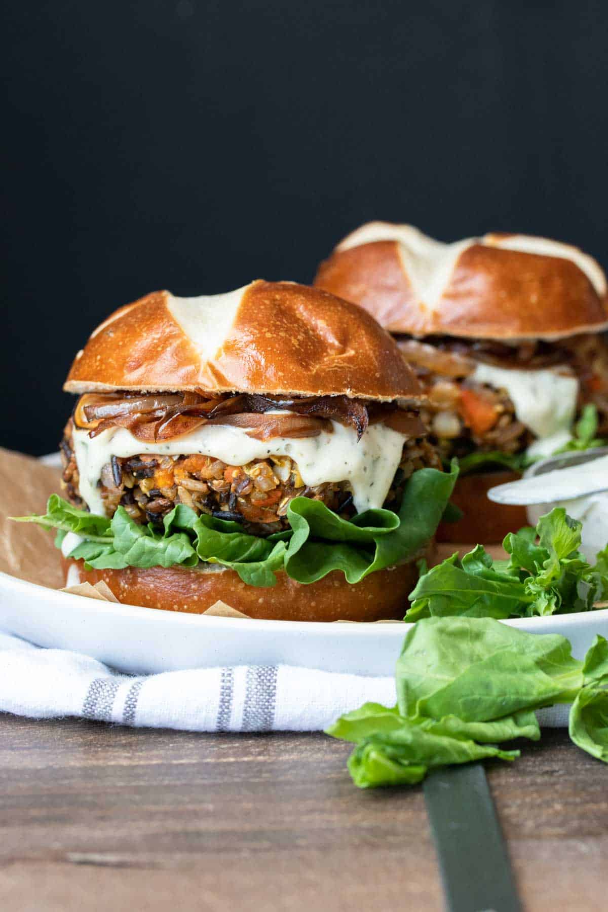 Front view of butternut squash burger on a pretzel roll with ranch, caramelized onions and lettuce.