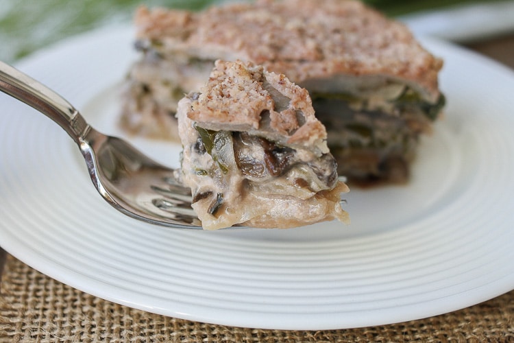 A fork picking up a piece of veggie casserole from a white plate