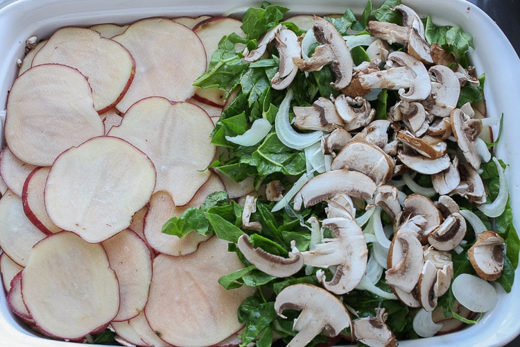 An overhead shot of sliced vegetables in a baking dish for making a veggie casserole