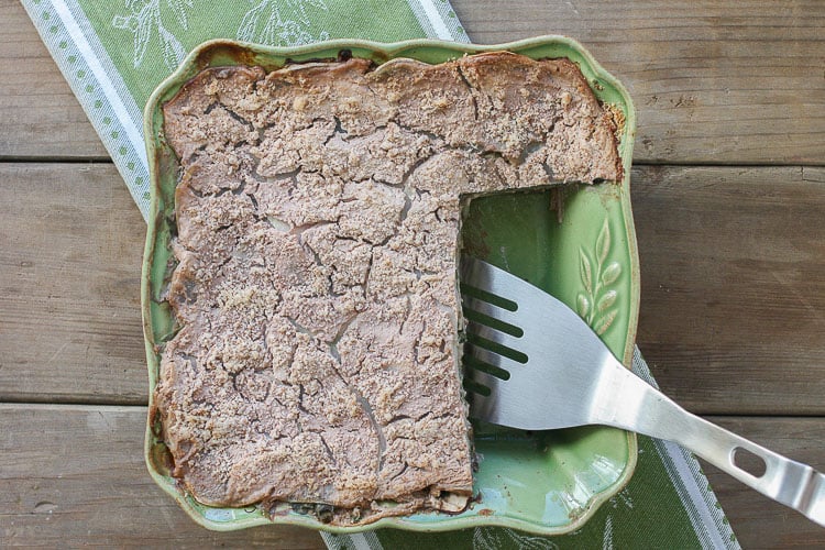 A green baking dish filled with a veggie casserole