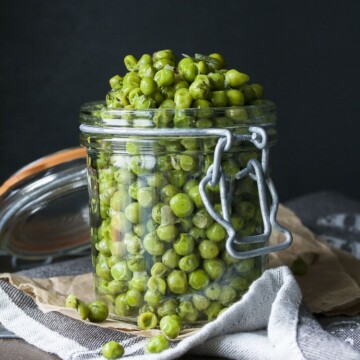 Cooked peas with scallions and dill piled high in a glass jar