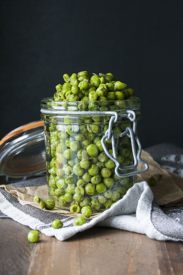 Cooked peas with scallions and dill piled high in a glass jar