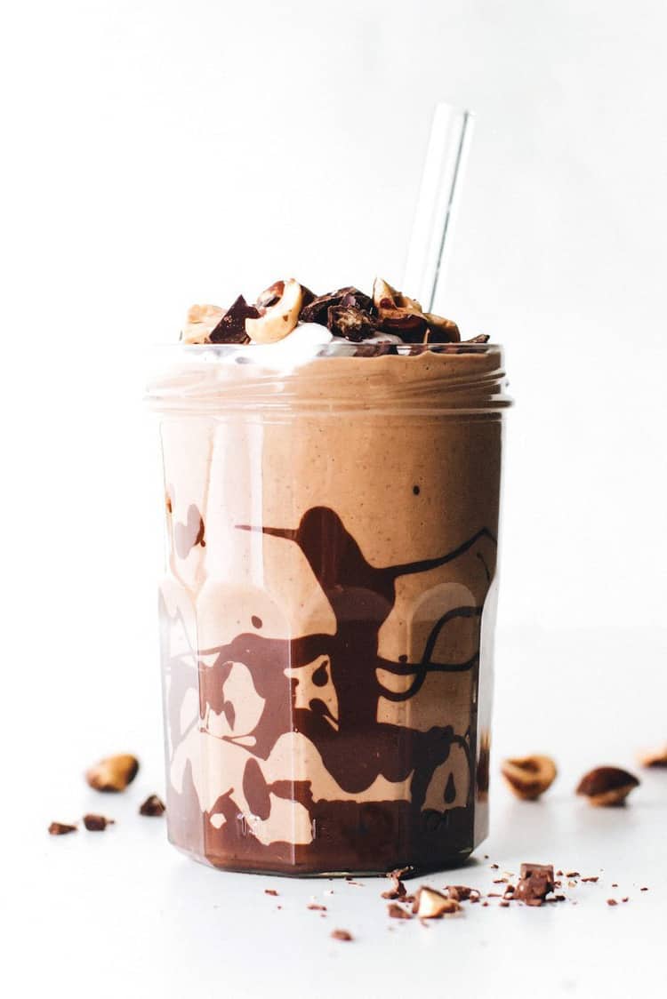 A glass filled with a chocolate milkshake with chocolate sauce