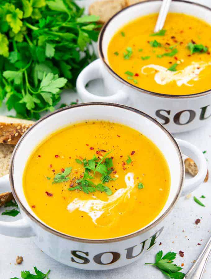 Two white soup bowls filled with creamy pumpkin soup