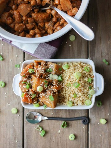 An overhead shot of a Korean Quinoa bowl with Chickpeas, Carrots & Potatoes on a wooden surface with a spoon