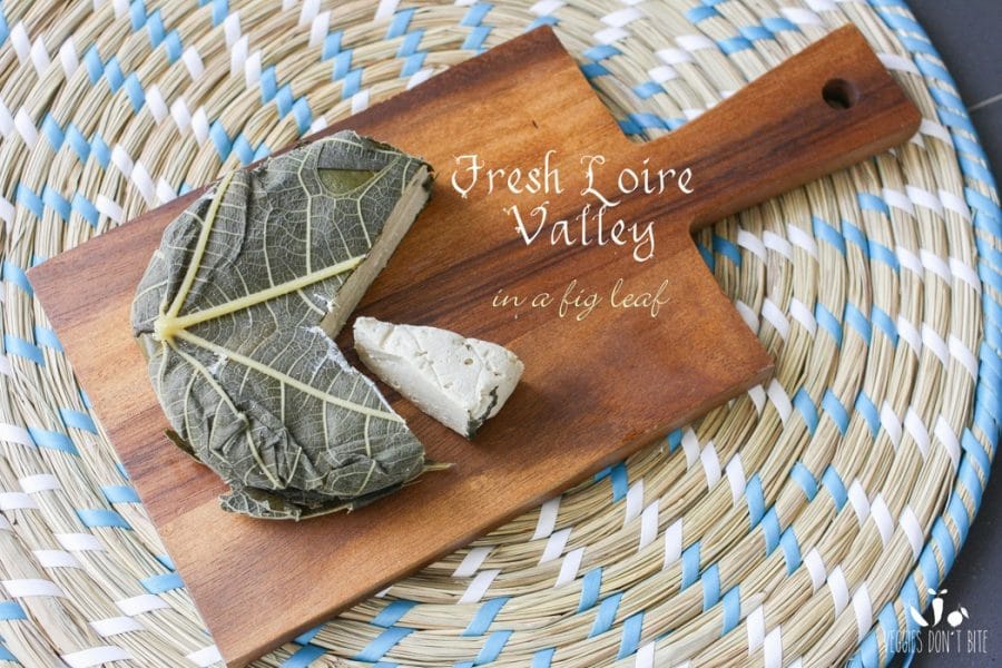 A photo of fresh loire valley Miyoko's Creamery Vegan Cheese wrapped in fig leaves sitting on a wooden chopping board