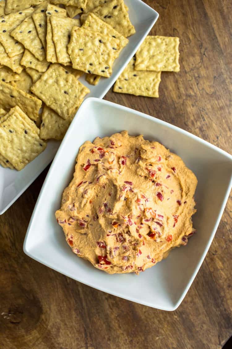 White bowl filled with a pimento cheese dip next to crackers